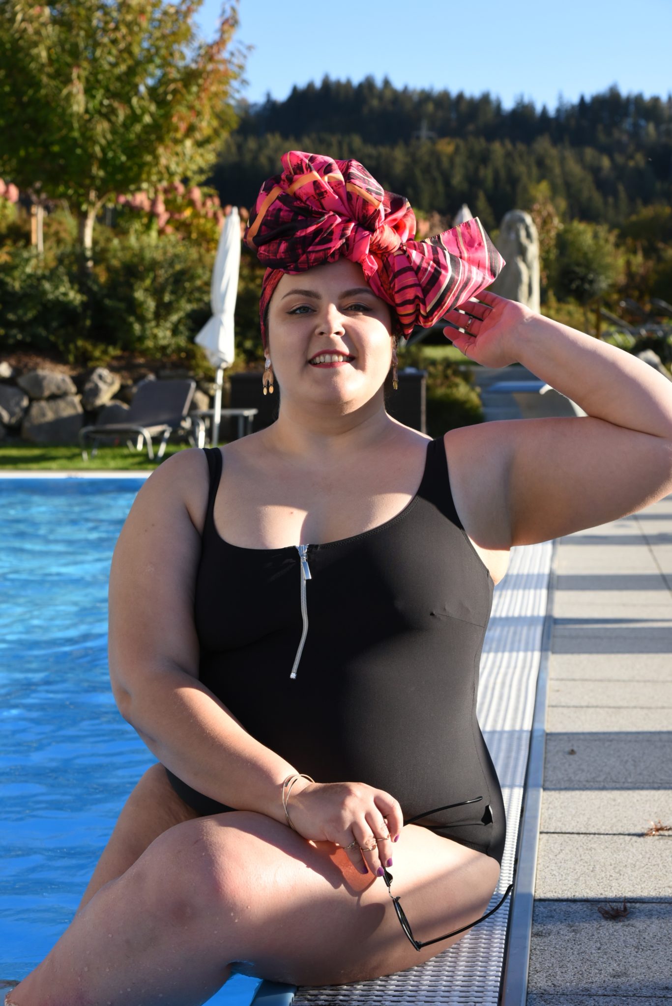Ubrana w czarny kostium, z różowym trubanem w kształcie kokardy Ula pozuje do zdjęcia na brzegu basenu
